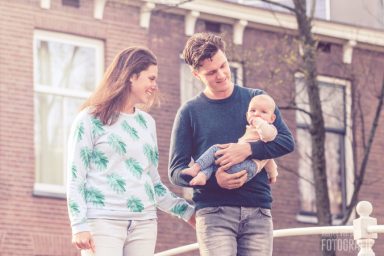 Een stel houdt een baby vast terwijl ze samen buiten wandelen.