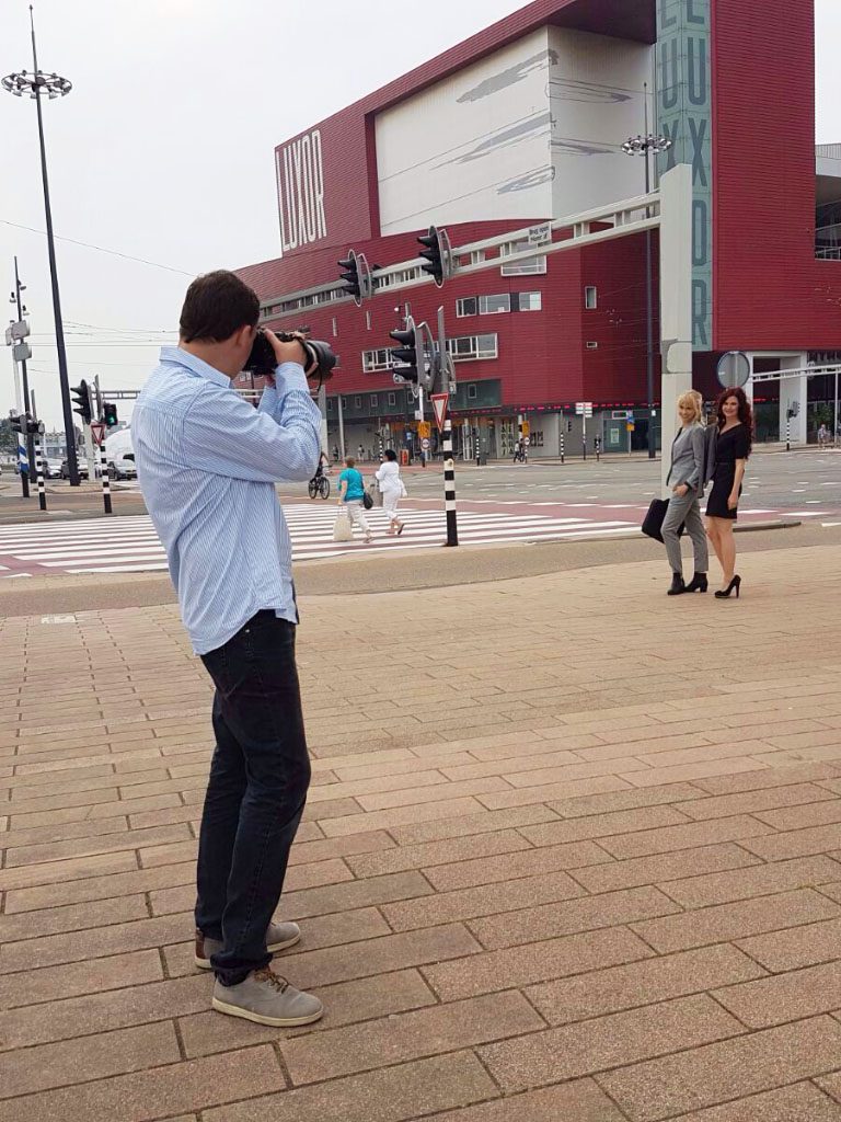 Man met camera fotografeert een vrouw in de stad nabij een winkelgebouw.
