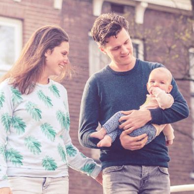 Een jong gezin wandelt samen in Delft; een vrouw en een man houden een baby vast.