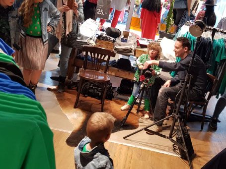 Kinderen in een winkel, één zit op een stoel terwijl een ander dichtbij kijkt.