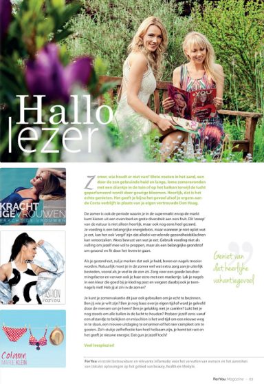 Twee vrouwen in een tuin, ontspannen zittend op een bankje, omringd door bloemen.