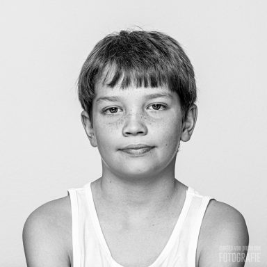 Portret van een jongen met kort haar en een neutrale gezichtsuitdrukking.