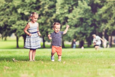 Een meisje en een peuter spelen op een grasveld in het park.