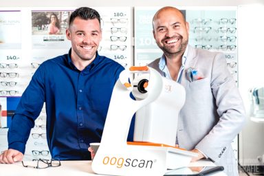 Twee mannen poseren naast een apparaat voor 3D-scans in een optiekwinkel.