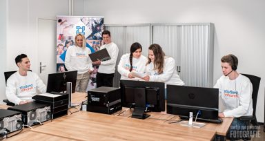 Een groep mensen in witte truien werkt samen aan computers in een moderne kantooromgeving.