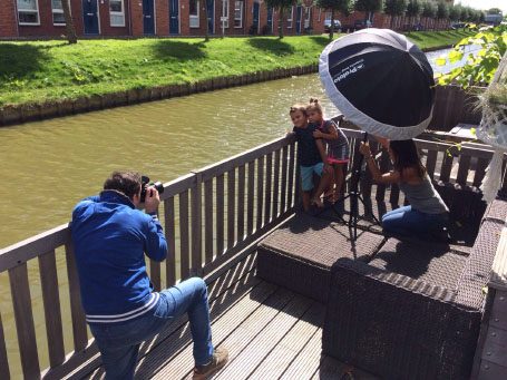 Een fotograaf maakt foto's van twee kinderen bij een sloot met een reflectorscherm.