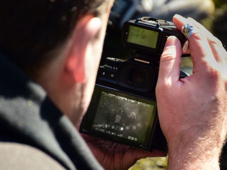 Een persoon fotografeert met een camera, terwijl hij het scherm bekijkt.
