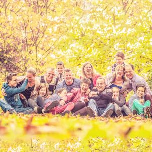 Groep van mensen zittend op de grond in een herfstlandschap met kleurrijke bladeren.