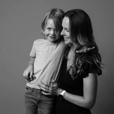 Een vrouw houdt een glimlachend kind vast, beide kijken elkaar liefdevol aan.