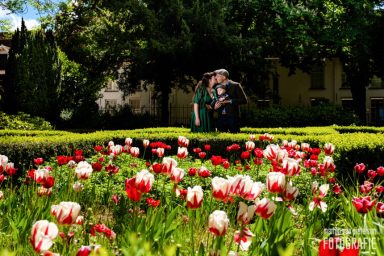 Groep mensen poseren tussen kleurrijke bloemen in een groene tuin.