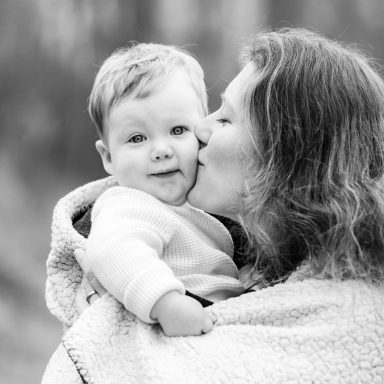 Zwartwit foto van een moeder die haar lachende baby kust.