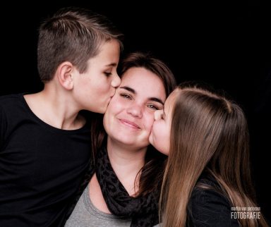 Een vrouw wordt gekust door een jongen en een meisje aan weerszijden.