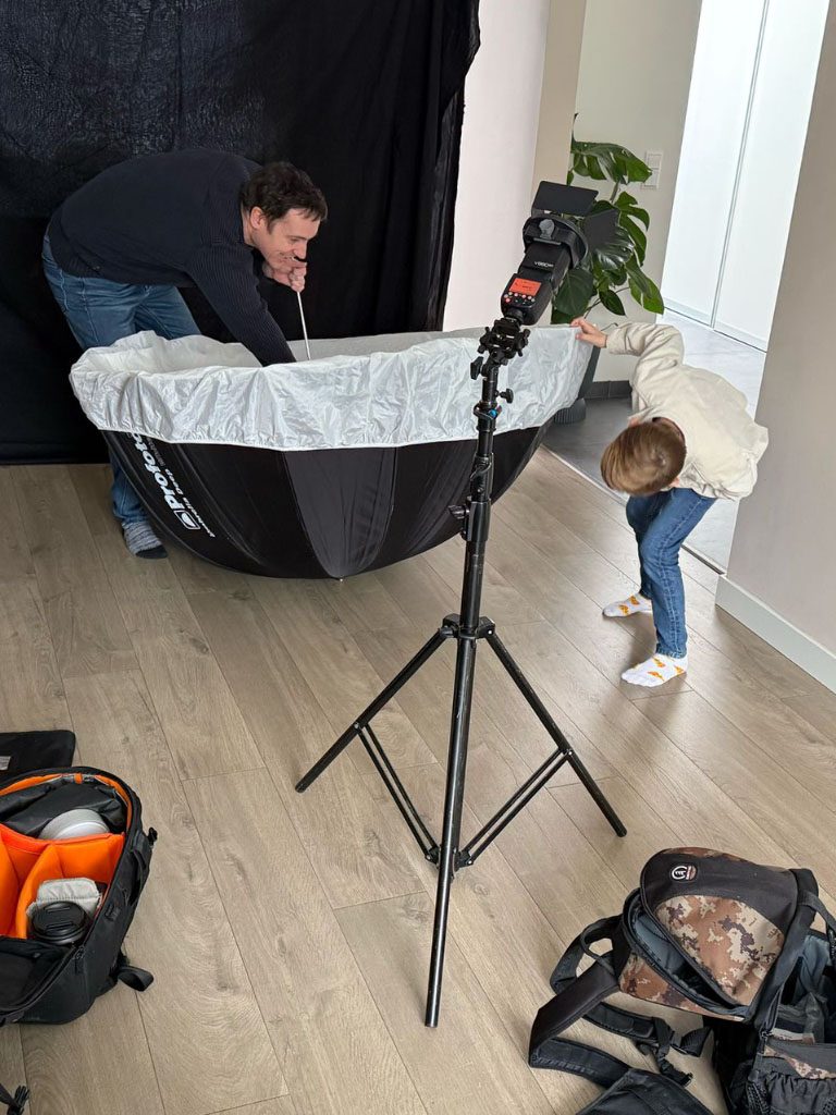Volwassene en een kind bereiden een fotostudio op met een opstelling en camera.
