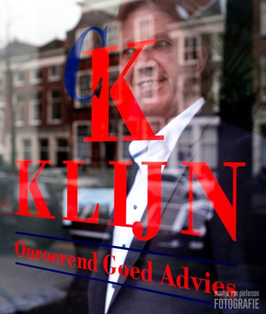 Reflectie van een man naast een raam met tekst.