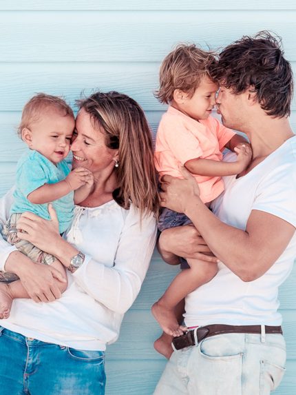 Een jong gezin poseert vrolijk met hun twee kinderen voor een strandhuisje in Hoek van Holland.
